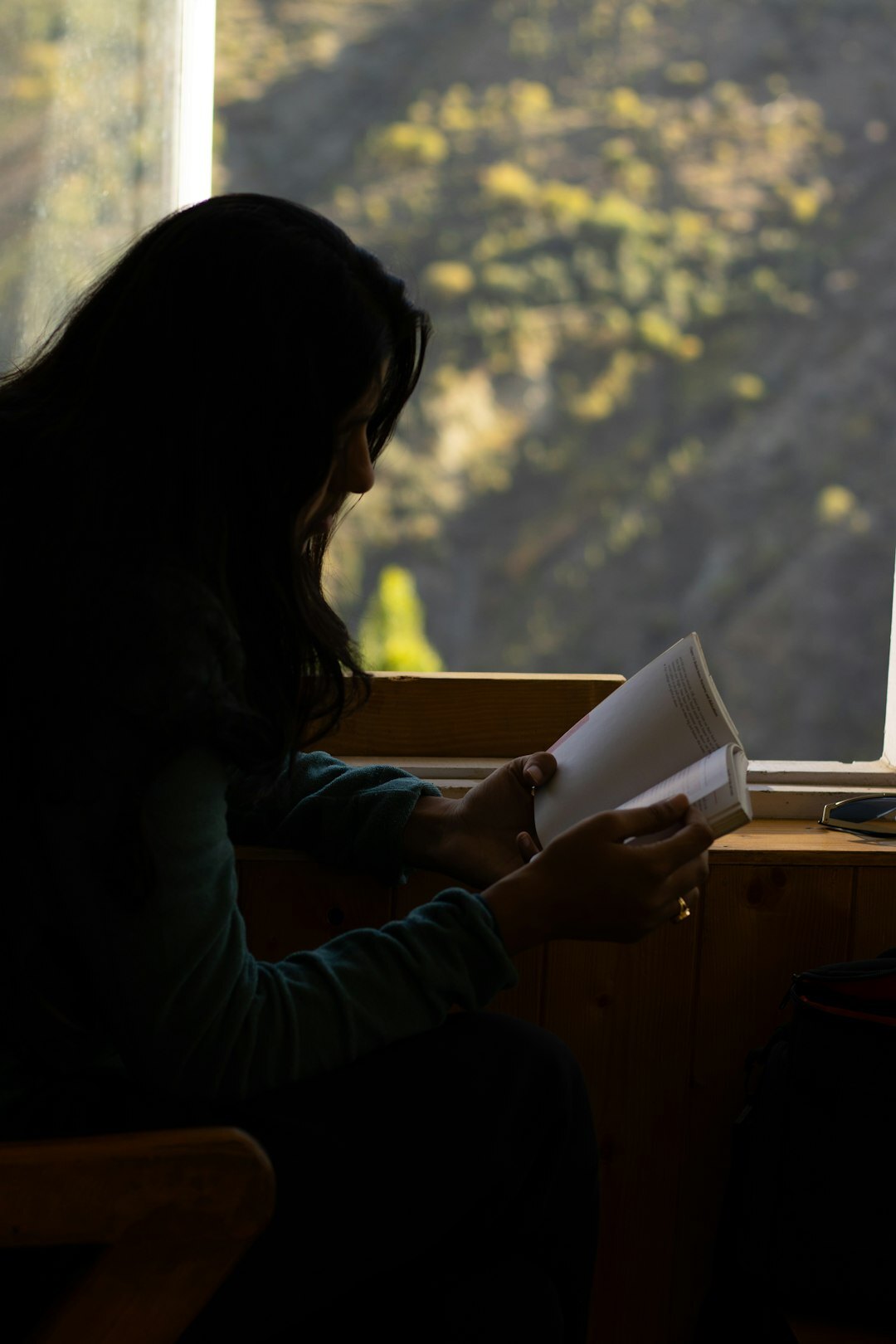 person reading book by window